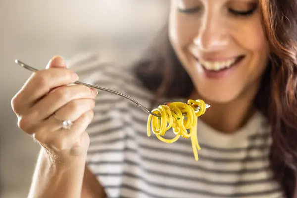 若い女性はスパゲッティを食べるのが好きです 彼は彼のフォークにひねられたAaglio Olioパスタを持っています ロイヤリティフリーのストック画像