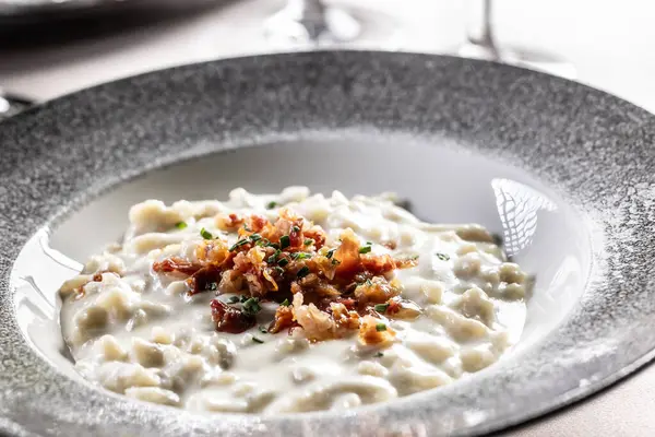 Geleneksel Slovak patates gnocchi peynirli bryndza, kızarmış domuz pastırması ve frenk soğanı modern bir tabakta servis edilir..