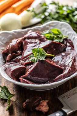 Dilimlenmiş sığır ciğeri beyaz bir kasede pişmeye hazır..