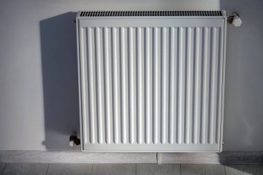 Beyaz bir duvara çelik bir ısıtma kaloriferi yerleştirilir..