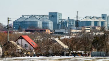 Tarımsal kompleksin arka planındaki köy ve tahıl deposu. Kış görünümü.