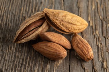 Kabuklu bademler kaba ahşap dokusunun arka planında. Seçici odak.  