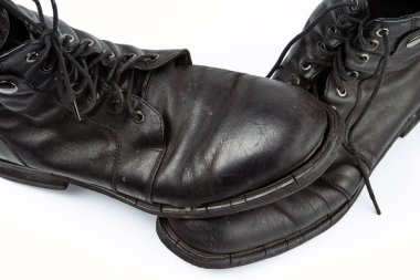 A pair of worn men's leather boots isolated on a white background