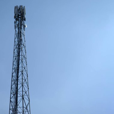 Mavi gökyüzüne karşı hücresel antenleri olan çelik kule.