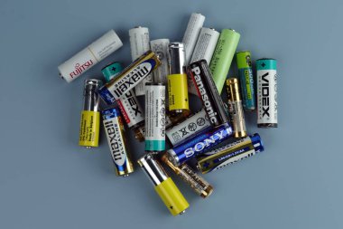 Kyiv, Ukrayna - 20 Mayıs 2023: Çeşitli üreticilerin kullanılmış ve hasarlı pilleri gri bir arka planda yatıyor. 