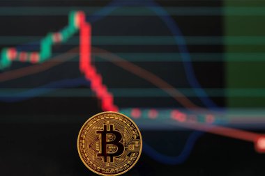 Bitcoin altın madeni para ve koyu arkaplanda aşağı doğru odaklanmış grafik. 