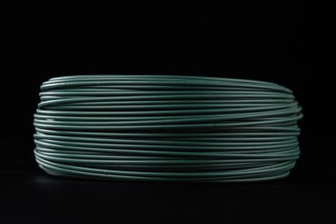 Yeşil PVC kaplamalı bir bobin. Siyah bir arkaplanda izole edilmiş.