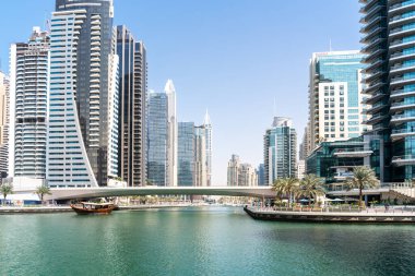 Dubai, Birleşik Arap Emirlikleri - 12 Mart 2023: Güneşli bir günde Dubai Marina 'da yürürken Dubai gökdelenleri ve geleneksel teknelerini görmek