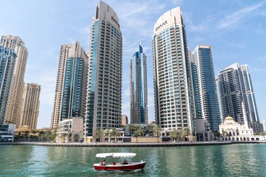 Dubai, Birleşik Arap Emirlikleri - 12 Mart 2023: Güneşli bir günde Dubai Marina 'da yürürken Dubai gökdelenleri ve geleneksel teknelerini görmek