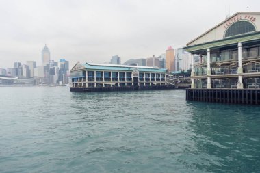 Hong Kong, 25 Mart 2019: Bulutlu bir günde Victoria Limanı 'ndaki dönme dolabın yanındaki Star Feribot iskelesinden Hong Kong gökdelenlerinin görüntüsü