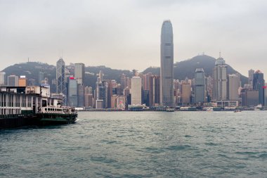 Hong Kong, 25 Mart 2019: Bulutlu bir günde feribottan geçen Hong Kong gökdelenlerinin görüntüsü