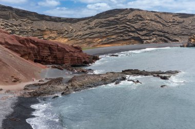 Lanzarote, İspanya - 10 Ağustos 2018: Lanzarote 'de Charco de los clicos adlı tuzlu su gölü yakınlarındaki teknelerin ve insanların manzarası bulutlu bir günde