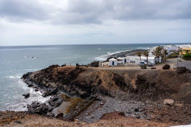 Lanzarote, İspanya - 10 Ağustos 2018: Lanzarote 'de Charco de los clicos adlı tuzlu su gölü yakınlarındaki küçük El Golfo kasabasının manzarası bulutlu bir gün.