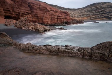 Lanzarote 'de Charco de los clicos adlı yeşil tuzlu su gölünün yanındaki Playa bulutlu bir günde