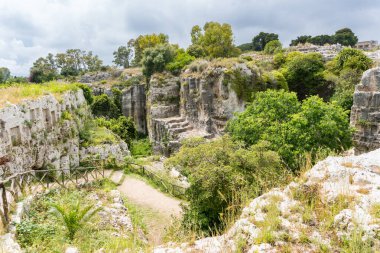 Syracuse, İtalya-9 Mayıs 2022: Roma döneminden kalma antik bir Yunan tiyatrosu, bir kilise, mağaralar ve diğer kalıntılarla birlikte Siraküza 'daki ünlü ve geniş doğal parkın görüntüsü.