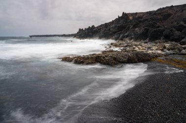 Bulutlu bir günde Tenesar yakınlarında terk edilmiş ve ıssız bir köy olan Lanzarote sahilinin manzarası.