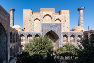 Semerkand, Özbekistan-Ağustos 12, 2023: Güneşli bir günde hatların saflığı ve majolikanın zarafeti ile ünlü 3 medreseden oluşan büyük bir tesis tarafından işgal edilen Registan meydanı.