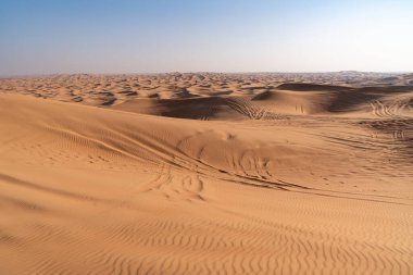 Dubai, Birleşik Arap Emirlikleri - 16 Mart 2023: güneşli bir günde Dubai yakınlarındaki çöl kum tepelerindeki off-road araçlarının lastik izleri