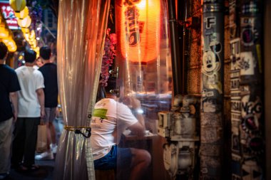 Tokyo, Japonya-Ağustos 5, 2024: İnsanlar akşam saatlerinde Shinjuku sokaklarındaki küçük yerlerde yemeğe ya da bir şeyler içmeye giderler.