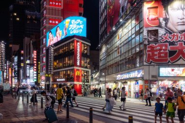 Tokyo, Japonya-Ağustos 5, 2024: İnsanlar Shinjuku 'daki yaya geçidinde geceleri neon ışıklarının arasında karşıya geçiyor.