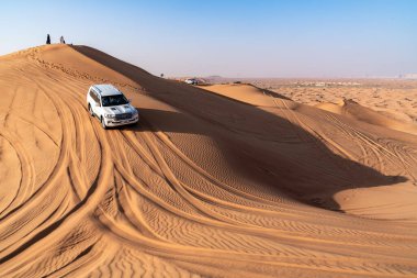 Dubai, Birleşik Arap Emirlikleri - 16 Mart 2023: off-road araçları ve güneşli bir günde Dubai yakınlarındaki çöl kumullarındaki insanlar