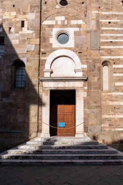 Lucca, İtalya-16 Şubat 2025: Güneşli bir günde San Frediano Bazilikasının yan kapısının dikey fotoğrafı
