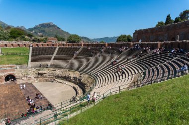 Sicilya, İtalya-12 Mayıs 2022: Turistler güneşli bir günde büyük antik Taormina tiyatrosuna hayran kalırlar.