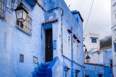 Şef, Fas. 26 Mart 2024. Merdivenler, bulutlu bir günde mavi şehir Chefchaouen 'de bir evin girişine çıkar.