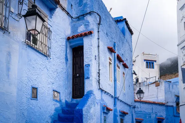 Şef, Fas. 26 Mart 2024. Merdivenler, bulutlu bir günde mavi şehir Chefchaouen 'de bir evin girişine çıkar.