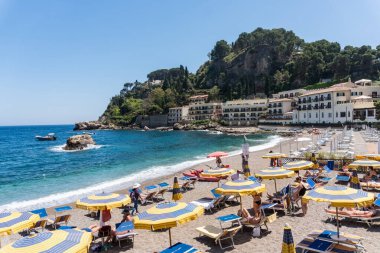 Sicilya, İtalya-12 Mayıs 2022: Güneşli bir günde Taormina 'daki Isola Bella plajında konaklama tesisleri, şemsiyeler ve turistler