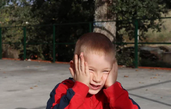 Ένα Κοντό Ξανθό Αγόρι Τεντώνει Μάγουλά Του Τις Παλάμες Του — Φωτογραφία Αρχείου