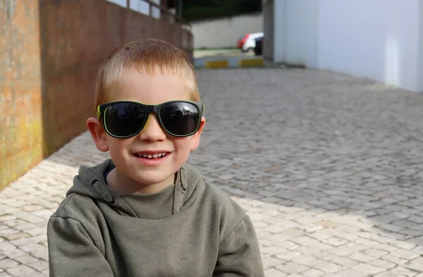 短髪の金髪の少年はカメラをまっすぐに見て笑顔を浮かべる サングラスをかけた５歳の少年 — ストック写真