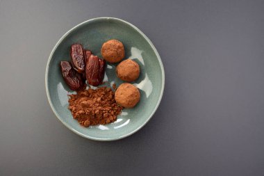 Enerji dolu hurma topları ve gri arka planda yuvarlak bir kasede kakao. Vejetaryen mantarı. Basit ve sağlıklı bir atıştırmalık..
