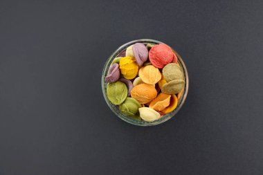 Kuru İtalyan renginde, pişmemiş, gri arka planda yuvarlak bir kasede turşulu makarna..