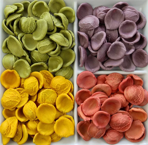 Kuru İtalyan renginde, yakın planda pişmemiş Orecchiette makarna. Pembe, leylak, sarı ve yeşil pasta.. 