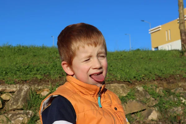 金髪の少年は目を細めて舌を出した 不満を抱いていた5歳の少年 — ストック写真