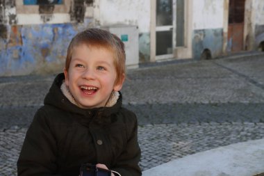 Sarışın çocuk yukarı bakar ve gülümser. Neşeli beş yaşında bir çocuk. 