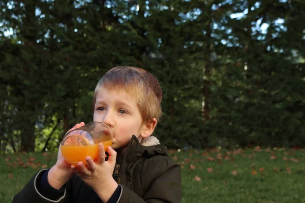 Blonďatý Chlapec Pije Pomerančový Džus Skleněné Láhve — Stock fotografie