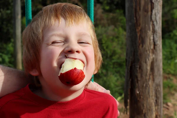 Blondyn Zawęził Oczy Trzymał Czerwone Jabłko Ustach Niegrzeczny Pięcioletni Chłopiec — Zdjęcie stockowe