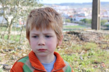 Sarışın çocuk kaşlarını çattı ve düşünceli bir şekilde uzaktan baktı. Üzgün beş yaşındaki çocuk..