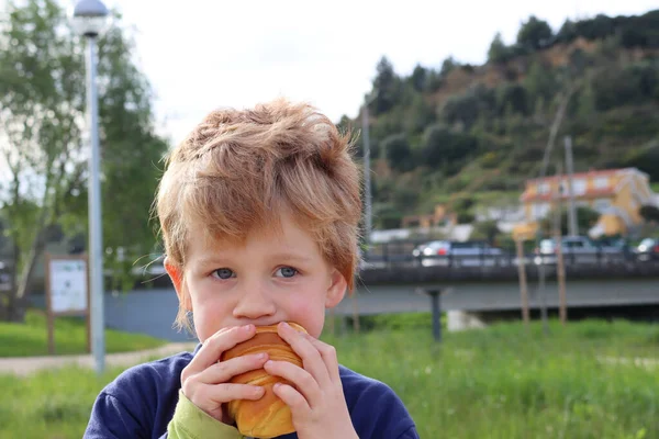 Blonďatý Chlapec Kousne Croissantu Zamyšleně Podívá Dálky Vážně Pětiletý Chlapec — Stock fotografie