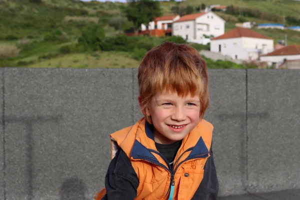 ポルトガルの家の屋根の上に笑顔の赤い髪の少年の肖像画 興味津々の距離を覗き込む5歳の少年 — ストック写真