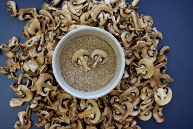 Kuru mantarların arka planında yuvarlak bir kasede mantar tozu..