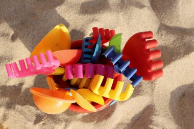 Arka planda çok renkli çocuk tırmıkları ve kürekleri var. Plaj için çocuk oyuncakları. Yukarıdan görüntüle.