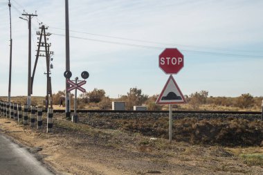 Aktau, Kazakistan (Kazakistan), 21.10.2023 - Bariyersiz bir demiryolu geçidi. Yol işareti Dur ve yapay kambur.