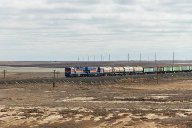 Aktau, Kazakistan (Kazakistan), 21.10.2023 - Kazakistan bozkırlarına giden bir yük treni. Bir yük treni, petrol ürünleri ve yük arabalarıyla tankları sürüklüyor.