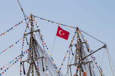 Bir geminin direğinde Türk bayrağı. Geminin direği çok renkli bayraklarla süslenmiş. Türkiye 'de Gemi Gezisi.