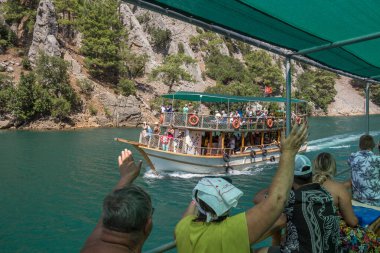Türkiye, Manavgat, 07.09.2023: Türkiye 'deki Yeşil Kanyon Gezisi. Turistler geçen bir gemiye el sallıyor. Türkiye 'ye Seyahat.