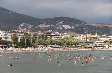 Türkiye, Alanya, 06.09.2023: İnsanlar Alanya 'daki Keykubat plajında dinleniyor ve yüzüyorlar. Türkiye 'de deniz tatili. Akdeniz kıyısında bir sahil. Alanya 'daki Keykubat plajında oteller ve gayrimenkuller.