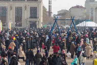 Uralsk (Oral), Kazakistan, 22.03.2024 - Kazakistan 'da Nauryz tatili. Bir grup insan ve Altybakan Nauryz bayramında salıncakta sallanıyor.